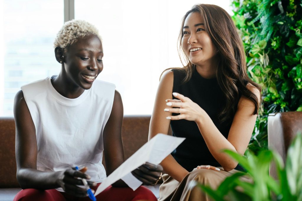 Multiethnic happy smiling women checking papers while speaking in comfortable conference hall in daytime